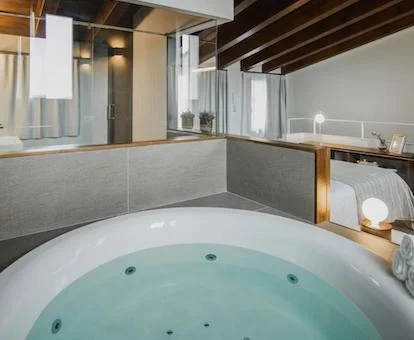 Jacuzzi circular junto a la cama del apartamento dúplex situado en un altillo con velas encendidas en el border