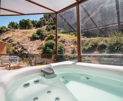 Jacuzzi para dos personas en la terraza de la habitación doble con bañera de hidromasaje con vistas al campo y las montañas.