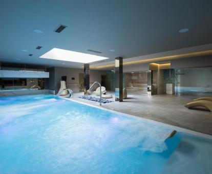 Amplia piscina con elementos de hidroterapia del centro de bienestar del hotel.