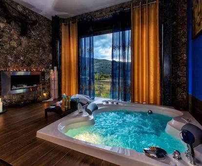 Foto del jacuzzi para dos personas funcionando con los chorros de hidromasaje y al fondo vemos una ventana con vistas al campo y enfrente una chimenea.