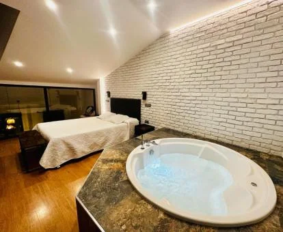 Dormitorio con un amplio jacuzzi junto a la cama de este precioso apartamento independiente.
