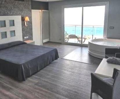 Preciosa suite superior con jacuzzi privado cerca de la cama y balcón con vistas al mar.