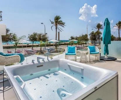 Jacuzzi en la terraza de la habitación Suite Sea Side Lovers con vistas al mar junto a dos sillas y dos hamacas con vistas al mar.