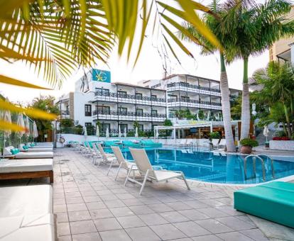 Hotel con encanto con piscina al aire libre rodeada de tumbonas.