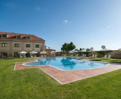 Amplia zona exterior ajardinada con piscina al aire libre de este hotel con encanto.