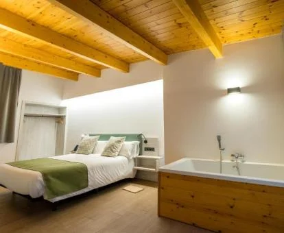 Bañera de hidromasaje cerca de la cama en la Habitación con cama grande y vistas al jardín del hotel.