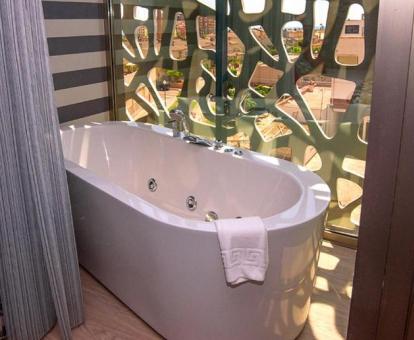 Bañera de hidromasaje privada junto a la cama en la Habitación Doble Deluxe con terraza del hotel.