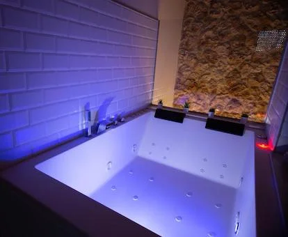 Foto del jacuzzi grande para dos personas con iluminación en morado que se encuentra junto a la cama en el apartamento Vistas de Chamberi